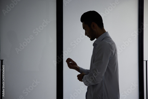 Foto Silhouetted man standing by window in thoughtful mood