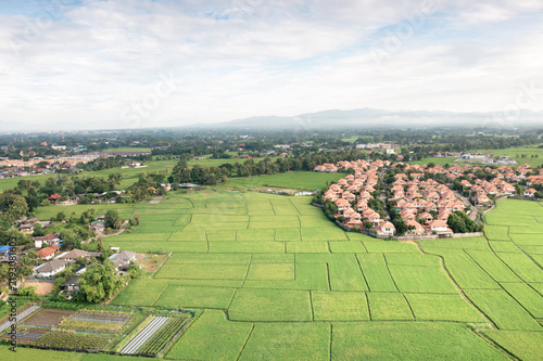 Aerial view of real estate property in San Sai, Chiang Mai, Thailand, featuring green farmland, residential estate, suburban community, land development, property investment, housing expansion.