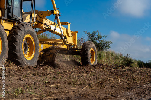 Yellow motor grader blade leveling dirt and soil on construction site roadwork