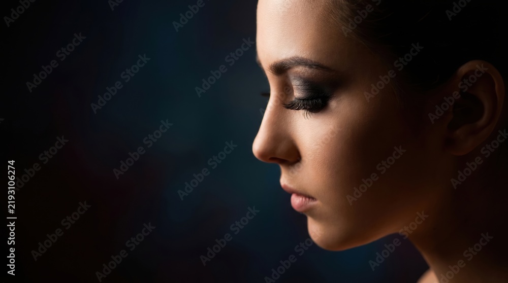 Fototapeta premium closeup profile portrait of caucasian woman with glamorous glitter eye makeup on dark background. dramatic beauty, cosmetics, elegance concept. copyspace. banner, website header, fashion magazine.