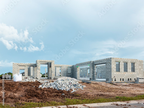 Quadro su tela Hurricane-resistant house under construction, with a bag of mortar mix (lower left) and piles of concrete-block castaways in front, in a suburban residential development in Florida