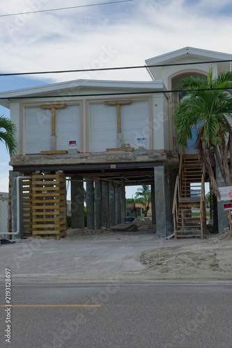 Foto A coastal two-story house raised on concrete pilings and temporary wooden suppor