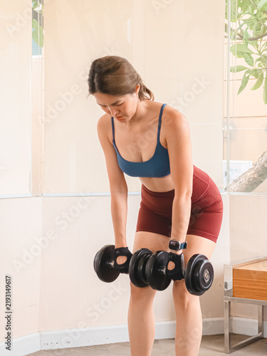 Young Asian Woman Performing Dumbbell Exercises at Home for Strength Training