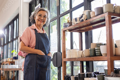 Cuadro en lienzo An elderly female artisan stands proudly in her ceramics shop, smiling as she welcomes customers