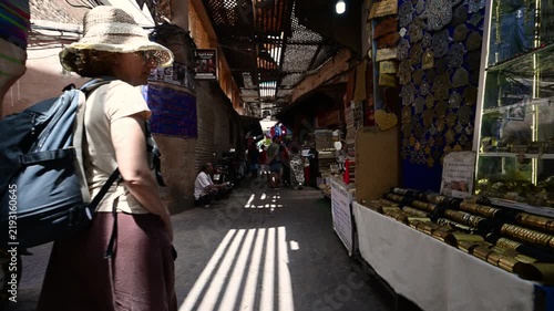 Marrakech, morocco. August 10, 2026. Female tourist with a backpack walking through a narrow, sunlit alley in a traditional souk in the medina of marrakech, morocco