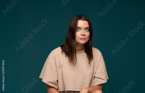 Картината върху платно Young woman showing wide-eyed surprise and shock on a dark teal background, reac