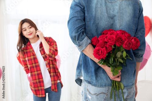 Konstfotografi Man hiding red roses behind back to surprise smiling woman