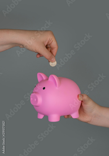 Konstfotografi Hand holds coin over piggy bank