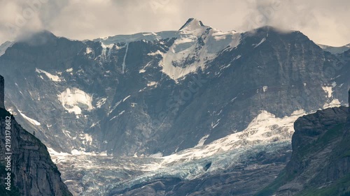 Grindelwald Switzerland alpine mountains timelapse with rushing clouds and moving shadows over majestic snow peaks and lower glacier valley slopes