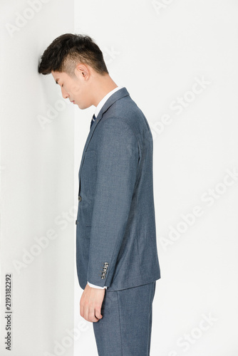 Obraz na płótnie Stressed businessman leaning against wall in despair
