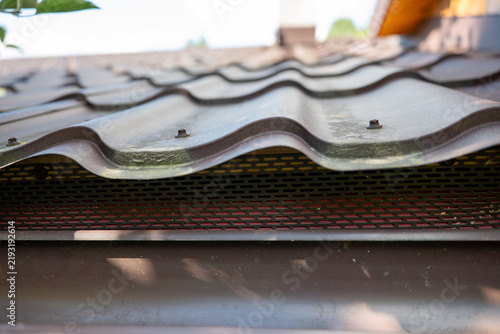 Perforated metal bird guard installed under profiled metal roof tiles, protecting the eaves from birds and small animals while allowing ventilation beneath the roofing.
