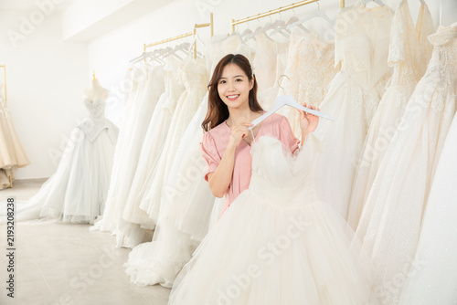 Happy bride choosing a wedding dress in a bridal shop