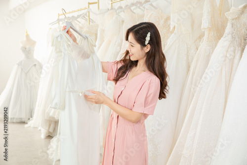 Happy bride choosing wedding dress in bridal shop