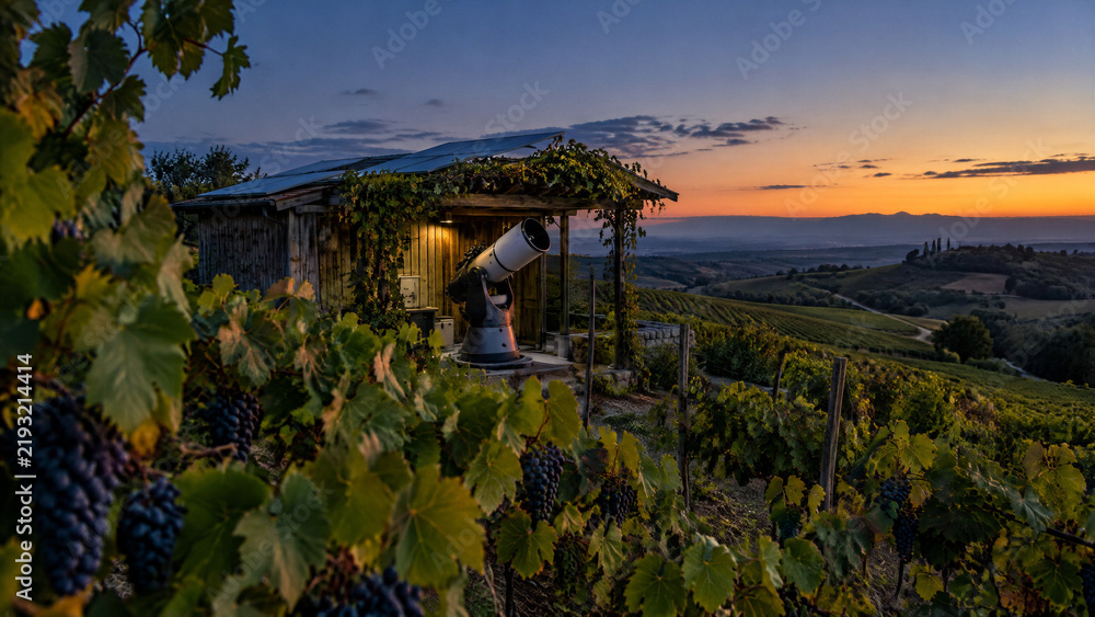 Obraz premium Telescope set up for stargazing in a vineyard at twilight with rolling hills in the background
