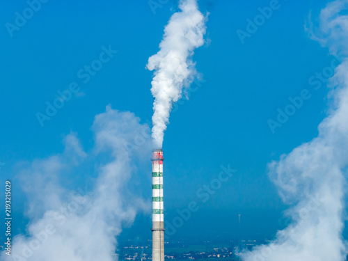 Foto factory smokestack emitting white smoke against blue sky