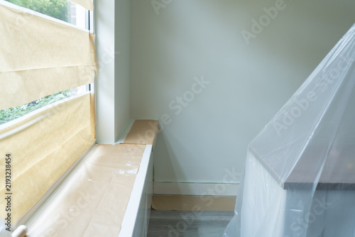 Furniture covered with protective film before room renovation, wall painting, and ceiling work to prevent dust and paint damage. 