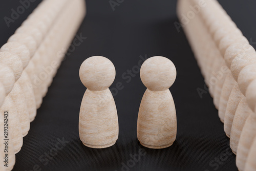 Foto Two wooden peg dolls standing face to face between two long rows of identical fi