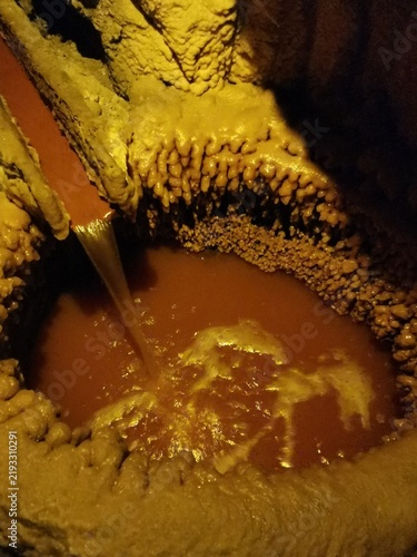 Obraz na plátně Salt formations drip over an amber-colored brine pool inside a natural chamber of the Wieliczka Salt Mine, Poland, September 16, 2022
