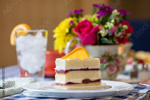Selective focus shot of delicious layer cake with jam between the layers and an orange slice.