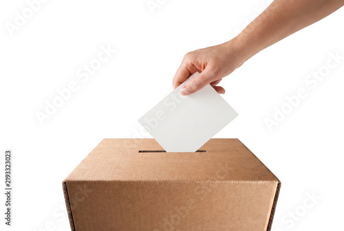 Hand inserting white ballot paper into cardboard voting box