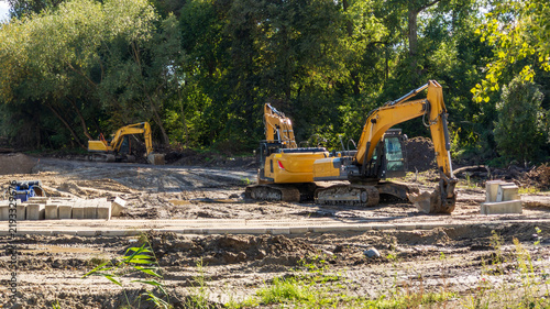 Quadro su tela Yellow excavators are carrying out earthworks to create a recreation area, involving soil movement, site preparation, and landscaping