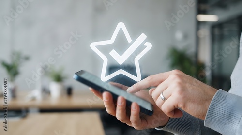Customer Satisfaction Concept: Close-up of Hands Using Smartphone with Glowing Star and Checkmark Icon for Five-Star Rating and Quality Approval in Modern Office