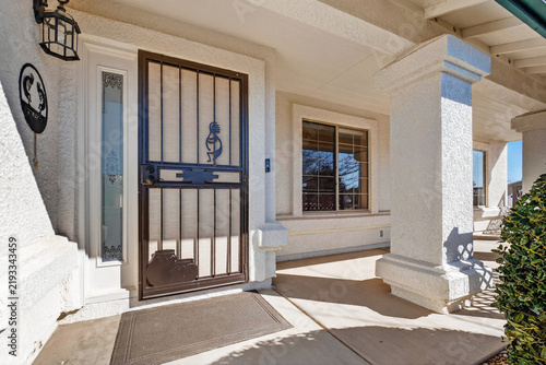 Front porch entry featuring stucco walls metal security gate arched sidelights and window front view