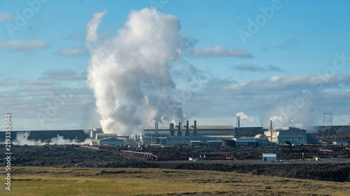 Foto Modern Svartsengi geothermal power plant emitting white steam plumes near Grindavik, Iceland, under a clear blue sky, symbolizing renewable energy