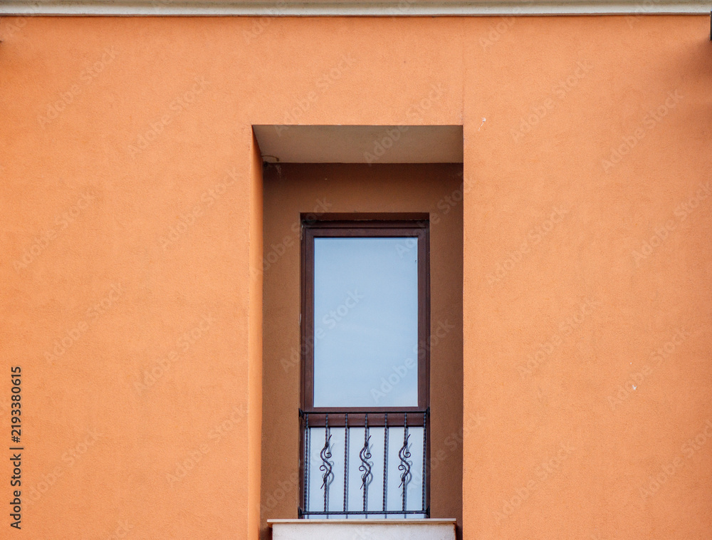 Fototapeta premium Minimalist modern window with wrought iron railing on orange plaster wall facade