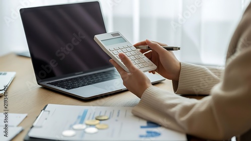 Professional businessperson calculating finances with a laptop and financial documents on a desk