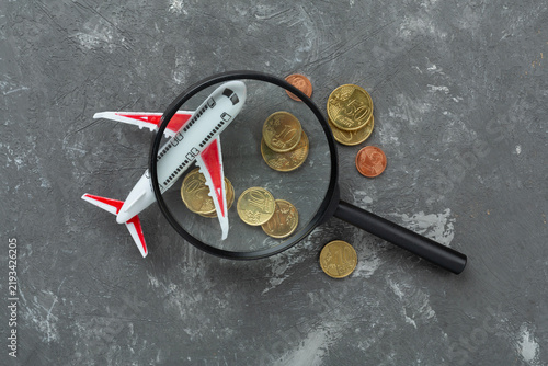 Model of airplane with coins on concrete background, top view