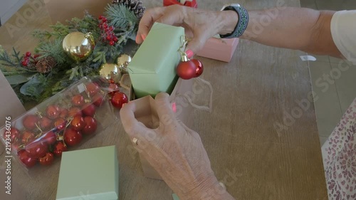 Woman preparing and wrapping christmas gift bags on a wooden table