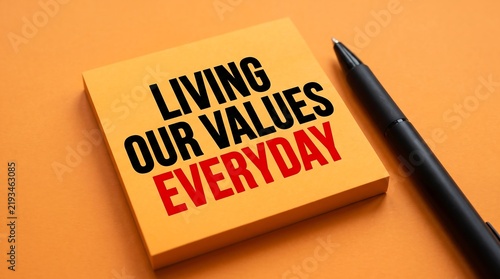Living Our Values Everyday inspirational text on sticky note, corporate culture and core values concept, motivational business message on orange background