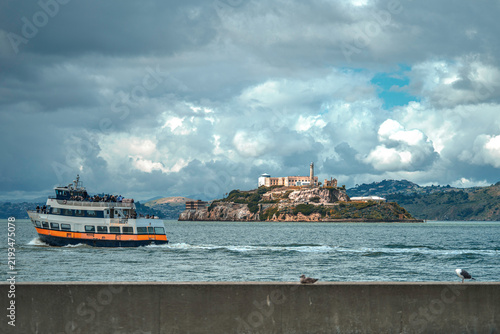 Ferry sailing in San Francisco Bay near Alcatraz Island under dramatic clouds
