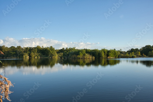 Obraz na plátně Clear blue sky and fluffy white clouds reflected in the calm, mirror-like waters