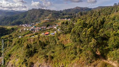 Aerial view of shola forest vegetation in Kookal, Palani Hills, Western Ghats, featuring Rudraksha, Jamun, cinnamon, grasslands, pine trees, and scattered village houses across the lush mountain lands