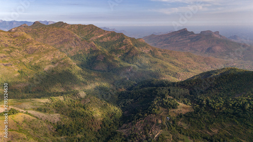 Wide aerial view of Kookal in the Palani Hills, Western Ghats, Tamil Nadu, overlooking shola forests, rolling grasslands, and layered monsoon clouds across a pristine lush highland landscape.