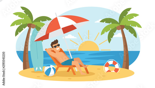 Happy young man relaxing on a beach lounge chair under a striped umbrella next to a surfboard on a tropical island.