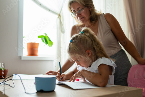 Mother helps daughter with homework at home. Family support, education and positive parenting