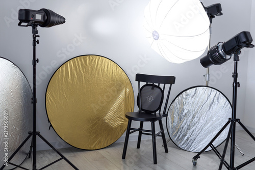 Different modern lighting equipment and chair in photo studio
