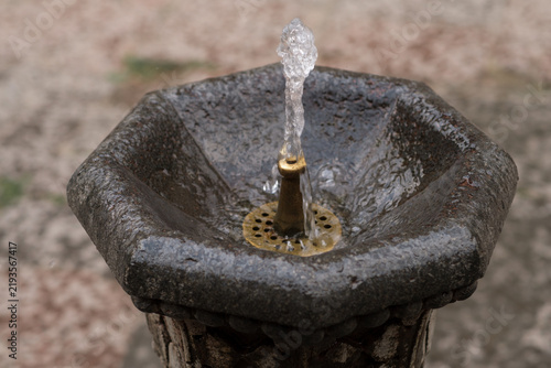 Foto Ornate stone fountain features water flowing from a central nozzle into a circul