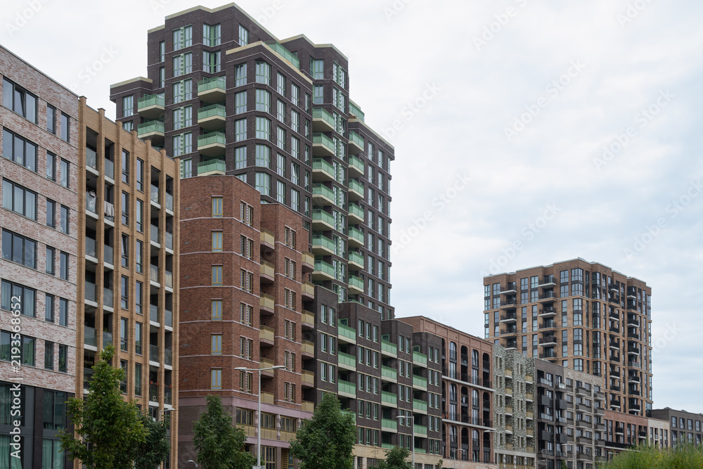 Fototapeta premium Contemporary apartment buildings with varied brick facades and arched windows along a street in the revitalized residential area of Amsterdam North, the Netherlands.