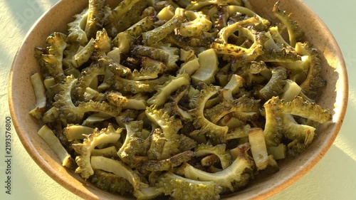 Fried bitter melon slices in a bowl, a key ingredient for stir-fried bitter melon with eggs. Table spin.