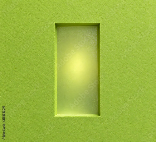 Rectangular opening in a lime green textured wall creates a bright focal point