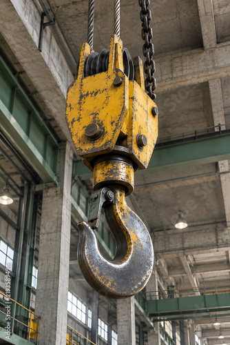 Industrial lifting hook with pulley system hangs within a concrete factory structure
