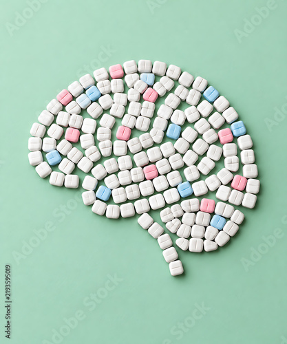 Pill formed brain shape constructed from pastel tablets on a mint green surface