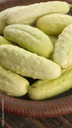 A clay plate holding ripe white cucumbers (White Wonder, a traditional American variety) placed on a rustic wooden surface. Table spin, natural lighting. Vertical video.