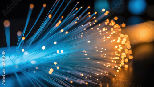 Bundle of illuminated fiber optic strands, broadband data connection background.