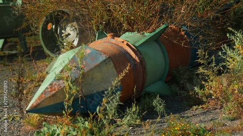Obsolete, abandoned, and rusty combat missiles and shells stand amidst the natural landscape. A weapons graveyard. An echo of war.