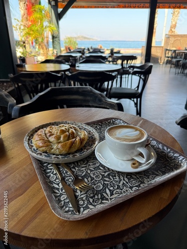 Morning coffee with pastry on a wooden table with a sea view in a cafe